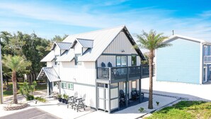 Ein zweistöckiges Gebäude mit Balkon, Sitzgelegenheiten im Freien und einem kleinen Garten.