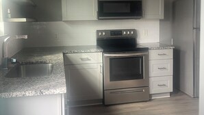 Een moderne keuken met roestvrijstalen apparatuur, witte kasten en een granieten aanrecht.
