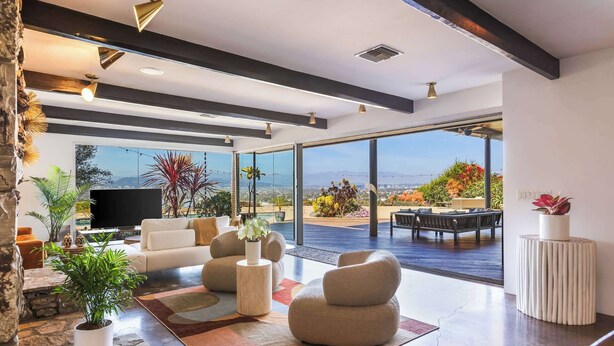 Una sala de estar moderna con un televisor grande, asientos cómodos y vistas al exterior.