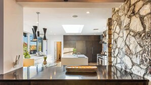 Una cocina moderna con una isla central, armarios de madera oscura y una pared de acento de piedra.