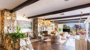 Un espacio habitable espacioso con chimenea de piedra, muebles modernos y un ventanal con vistas.