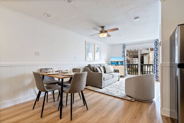 Un salon moderne comprenant un coin repas, un canapé et un ventilateur de plafond.