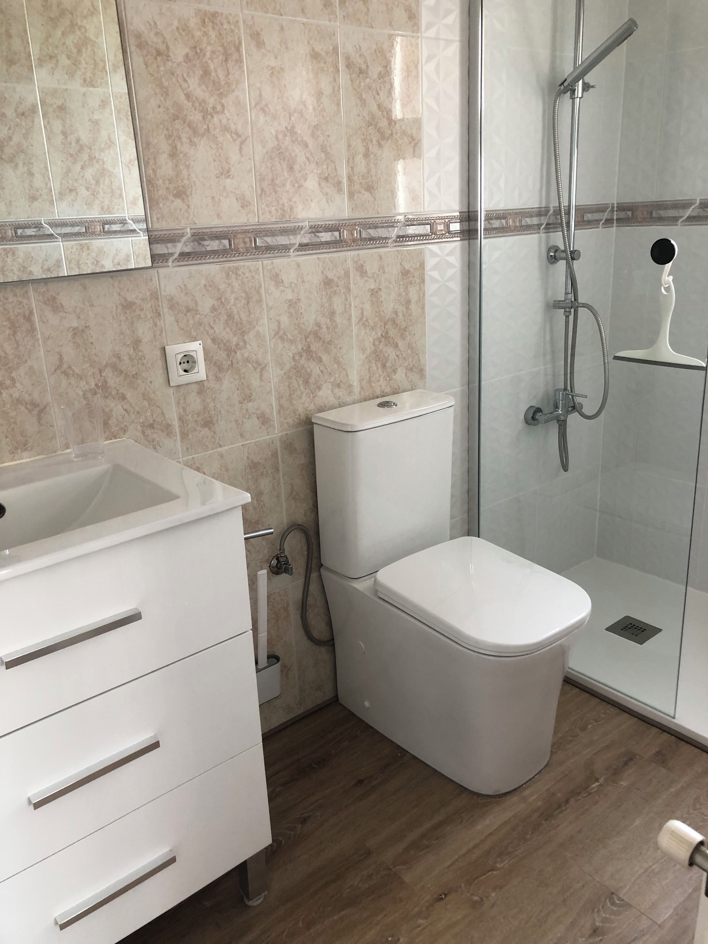 A modern bathroom with a toilet, a sink, and a shower.