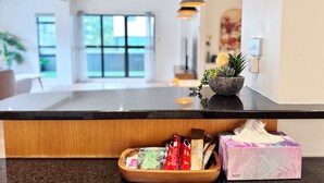 A hotel reception area with a wooden counter, a bowl of snacks, a tissue box, and a hanging pendant light. - Heart of Auckland 2BR Near Queen St & Skytower (Auckland)