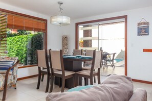 A dining area with a table set for four, surrounded by chairs, and a pool visible through the glass door.