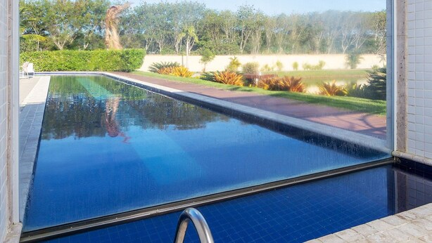 A swimming pool with a view of a landscaped garden and trees.