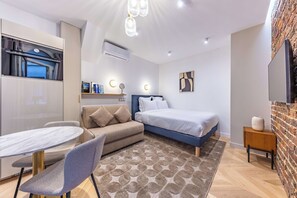 Un dormitorio moderno con cama, sofá, mesa de comedor y televisor.