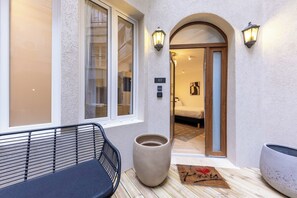 A hotel entrance with a wooden bench, a large planter, and a door marked with the number 02.