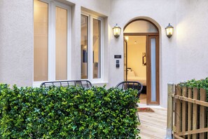 A hotel entrance with a wooden gate, a number '02' sign, and a well-maintained hedge.