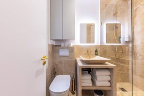 A modern bathroom with a toilet, sink, and shower.