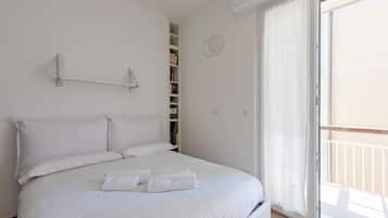 Un dormitorio con cama, armario y puerta corrediza de vidrio a un balcón.
