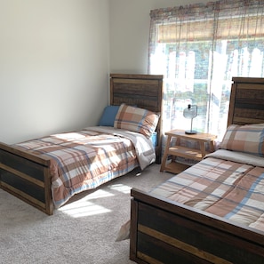 Una camera da letto con due letti di legno, un comodino e una finestra con tende.