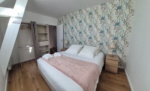 A bedroom with a bed, bedside tables, a wardrobe, and a patterned wallpaper.
