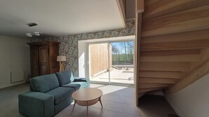 A living room with a sofa, a small table, a wooden cabinet, and a sliding glass door leading to an outdoor area.