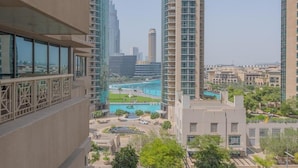 A high-rise building with a view of a swimming pool and surrounding greenery.