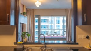 A modern kitchen with a stainless steel sink, a potted plant, and a view of a balcony with outdoor furniture.