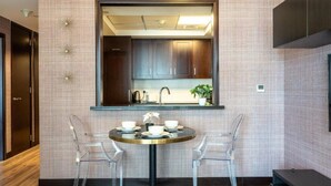 A modern kitchen with dark wooden cabinets, a round dining table with two chairs, and a small potted plant on the counter.