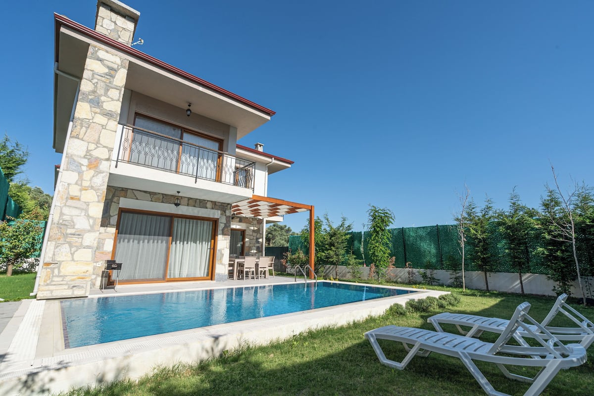 Une maison à deux étages avec une piscine, un patio couvert et un jardin.