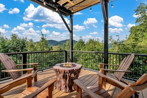 A wooden deck with a fire pit, two Adirondack chairs, and a pergola structure. - Wandering Bear (Black Mountain)