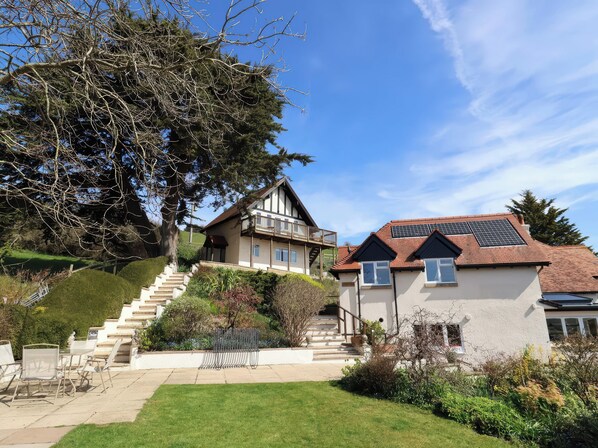 A two-story house with a balcony, a staircase leading to the upper floor, and solar panels on the roof.