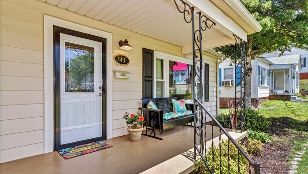A house with a front porch, a welcome mat, a number plaque, and a bench with cushions. - Quaint Mill Cottage (Marion)