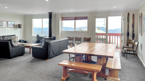 A spacious living area with a large wooden table and benches, a leather sofa, and a fireplace.