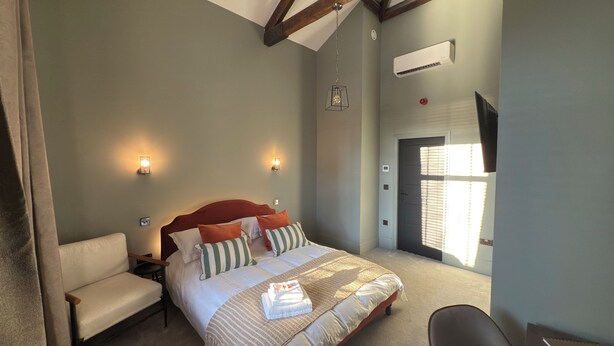 A bedroom with a bed, bedside tables, a chair, a desk, and a window with blinds.