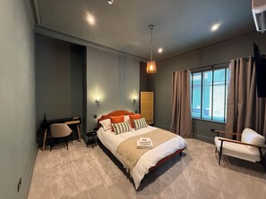 Un dormitorio moderno con una cama grande, un escritorio, una silla y un armario.