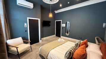A modern bedroom with a bed, a chair, an air conditioning unit, a ceiling light, and a wall-mounted TV.