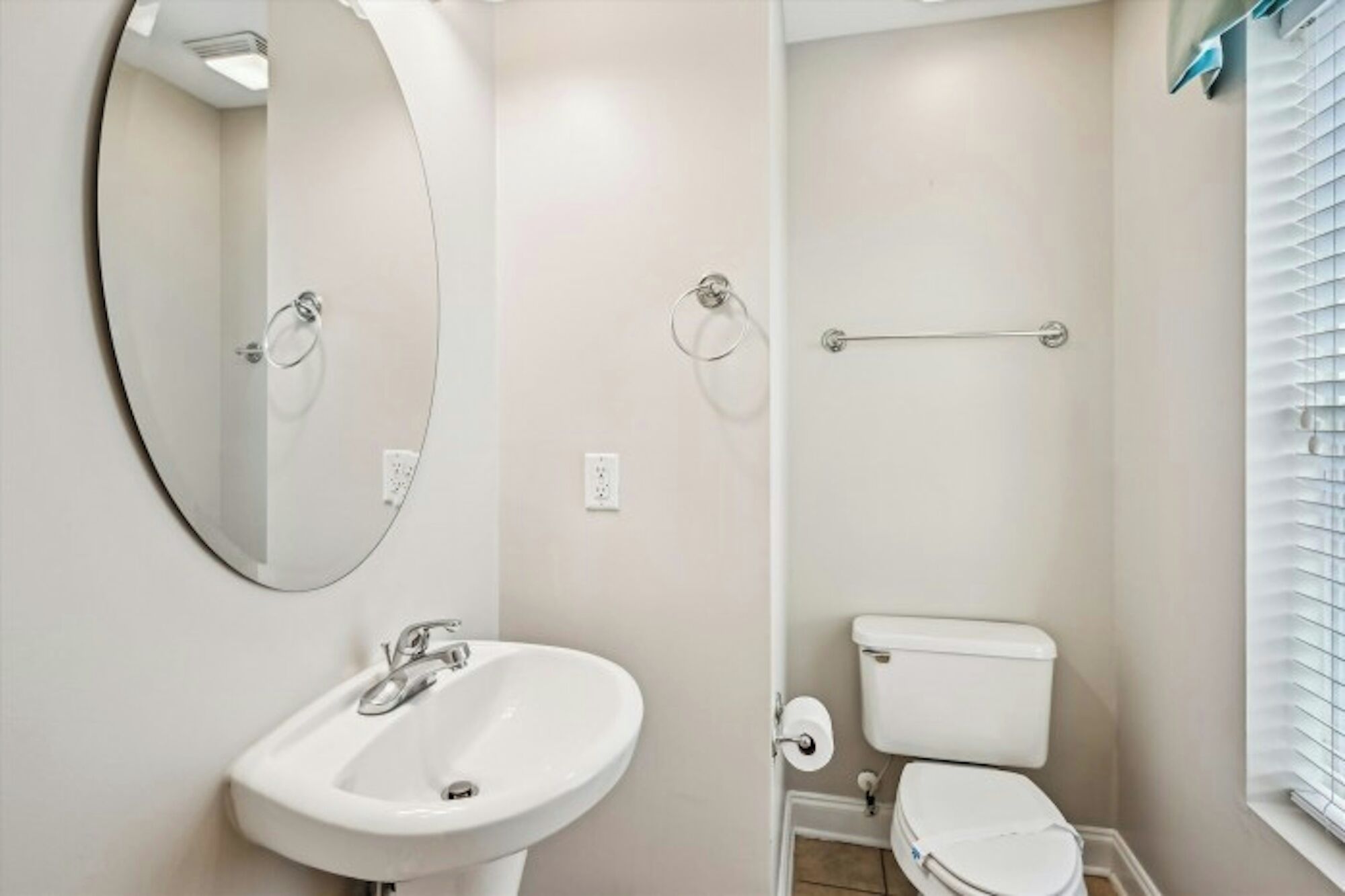 Un baño con lavamanos blanco, inodoro y espejo.