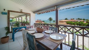 A dining area with a table set for four, a mirror, and potted plants. - Bz43 Casa em condominio pé na areia (Búzios)