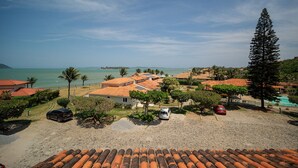 A coastal property with red-tiled roofs, a sandy beach, and a view of the sea. - Bz43 Casa em condominio pé na areia (Búzios)