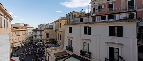 A bustling piazza surrounded by historic buildings with balconies and large windows.