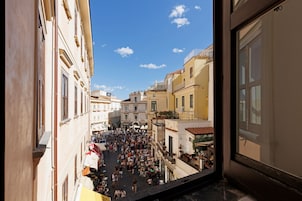 Escena de calle concurrida, con edificios y balcones.