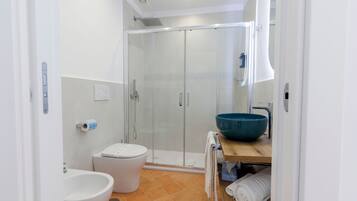Une salle de bain moderne avec une douche à parois de verre, des toilettes blanches, un grand lavabo bleu et un meuble-lavabo en bois.