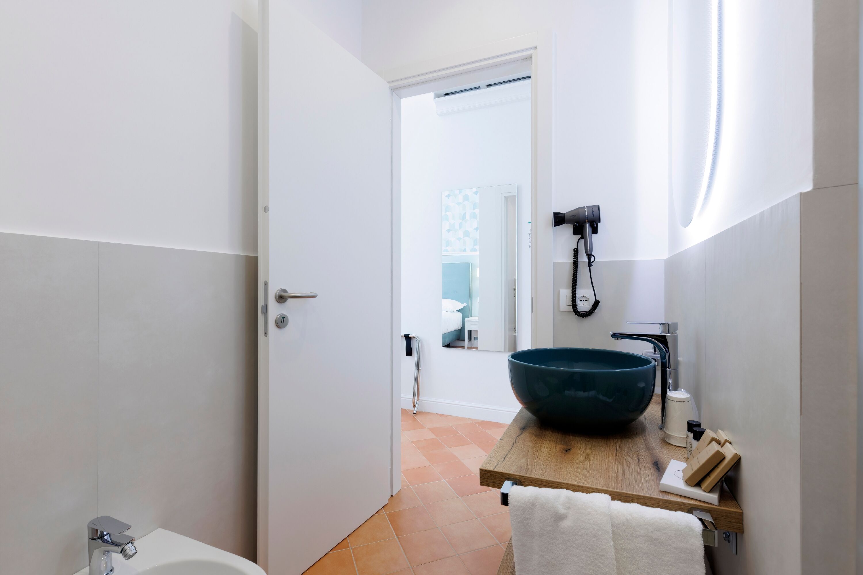 Un baño moderno con un lavabo grande, un cabezal de ducha manual y un perchero para toallas.