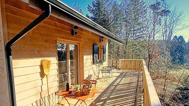 En stuga av trä med en veranda, ett fönster och en dörr.