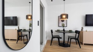 A modern dining area with a round table, black chairs, and pendant lighting. - Amber - by Kairos Apartments (Gliwice)
