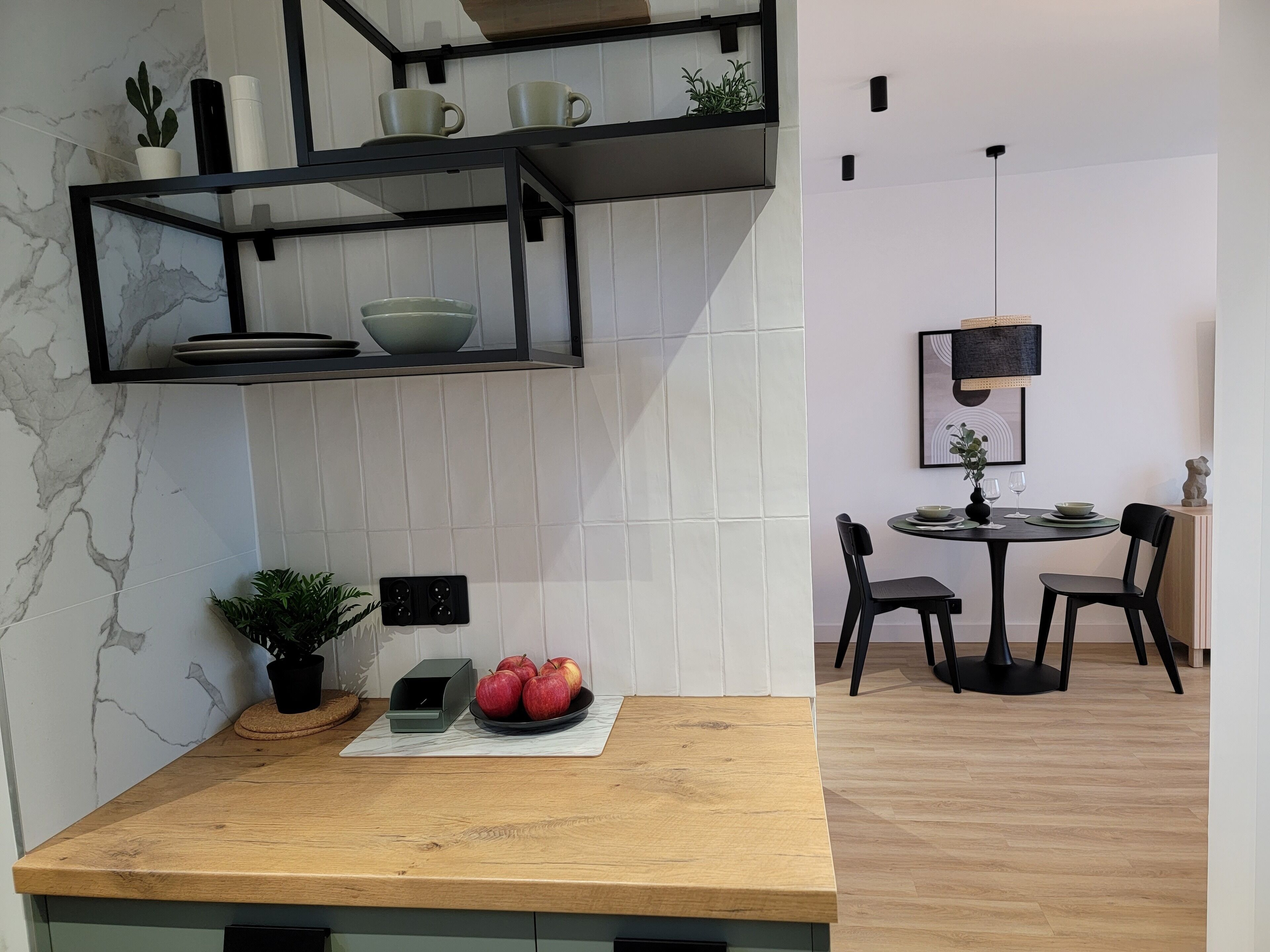 A modern kitchen with a marble backsplash, a wooden countertop, and a dining area with a round table and chairs.