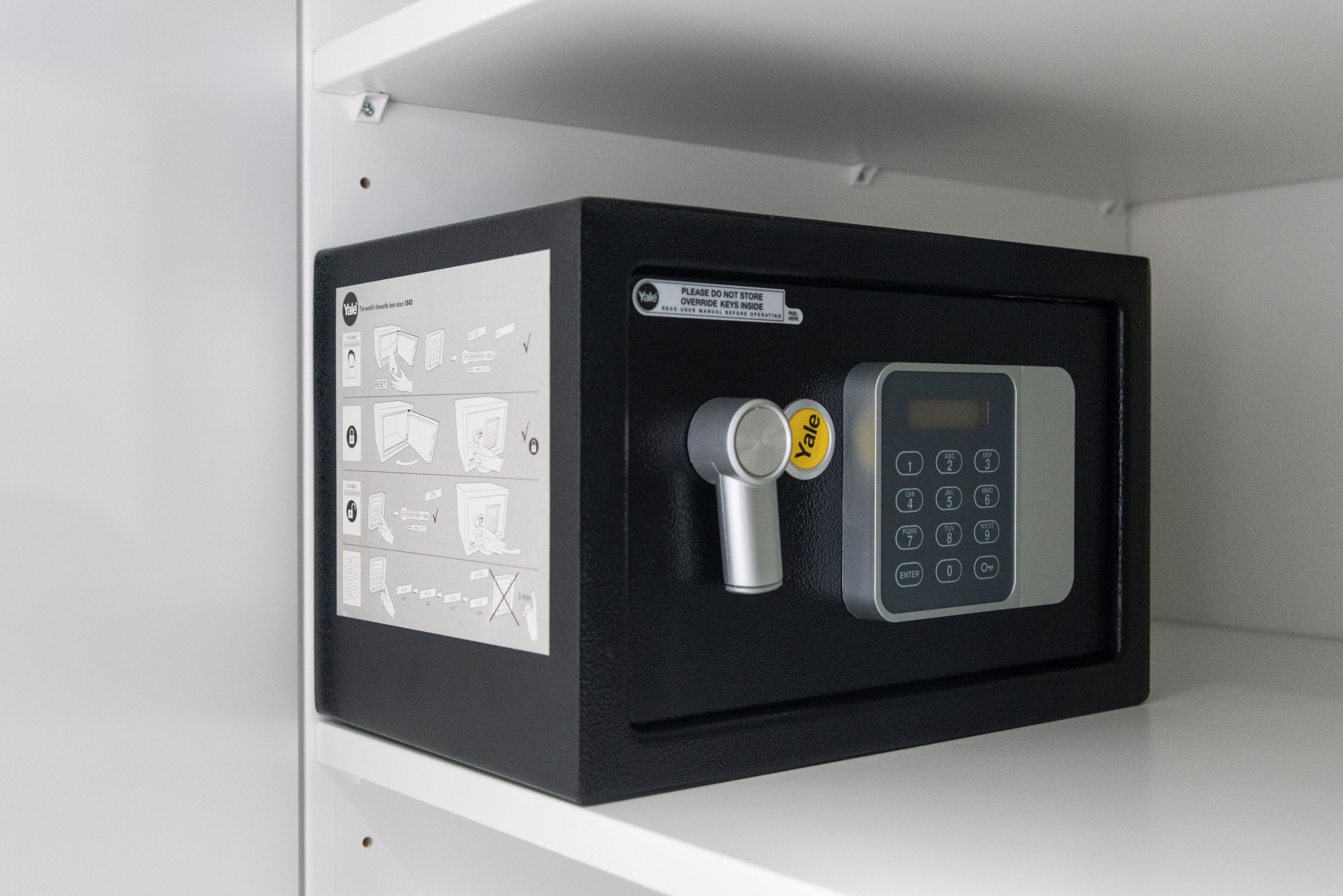 A security keypad with a warning label and a small cylindrical object beside it.