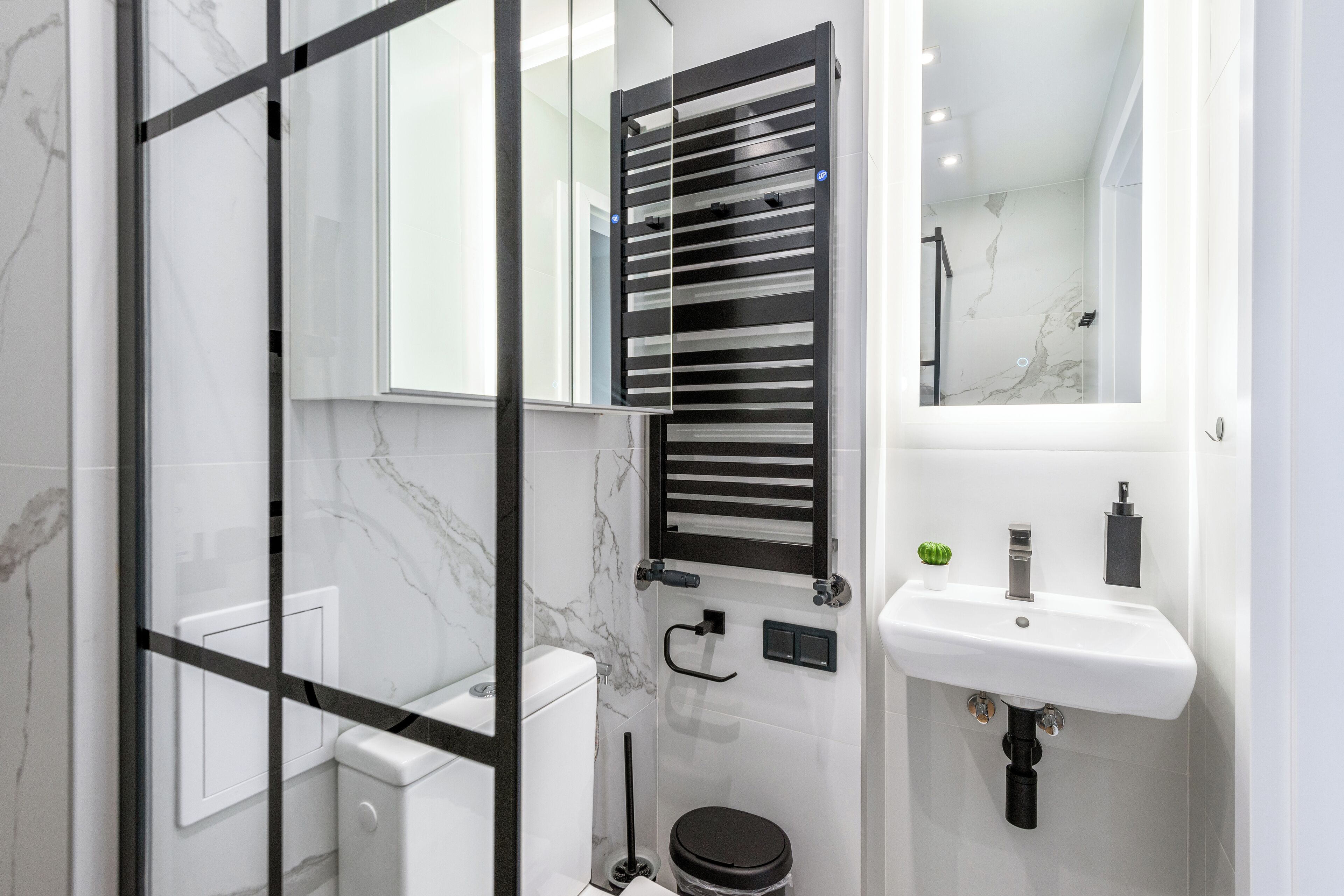 Un bagno moderno con cabina doccia in vetro, un water, un lavandino e un porta asciugamani.