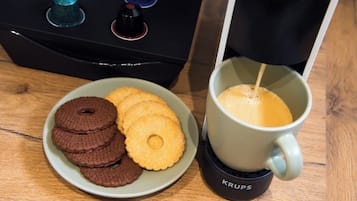 Um prato de biscoitos e uma máquina de café sobre uma mesa.