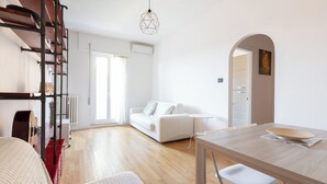 Una sala moderna con un sofá blanco, una mesa de comedor de madera y un mueble de almacenaje rojo.