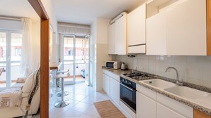 Una cocina moderna con armarios blancos, microondas integrado y cocina a gas.
