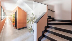 Un interior moderno con una escalera, un pasillo con una planta y una puerta.