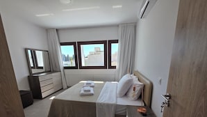 Un dormitorio moderno con una cama grande, una mesita de noche, un tocador y un espejo.