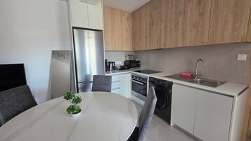Una cocina moderna con armarios blancos, un refrigerador de acero inoxidable, un horno empotrado, un lavavajillas y un fregadero.