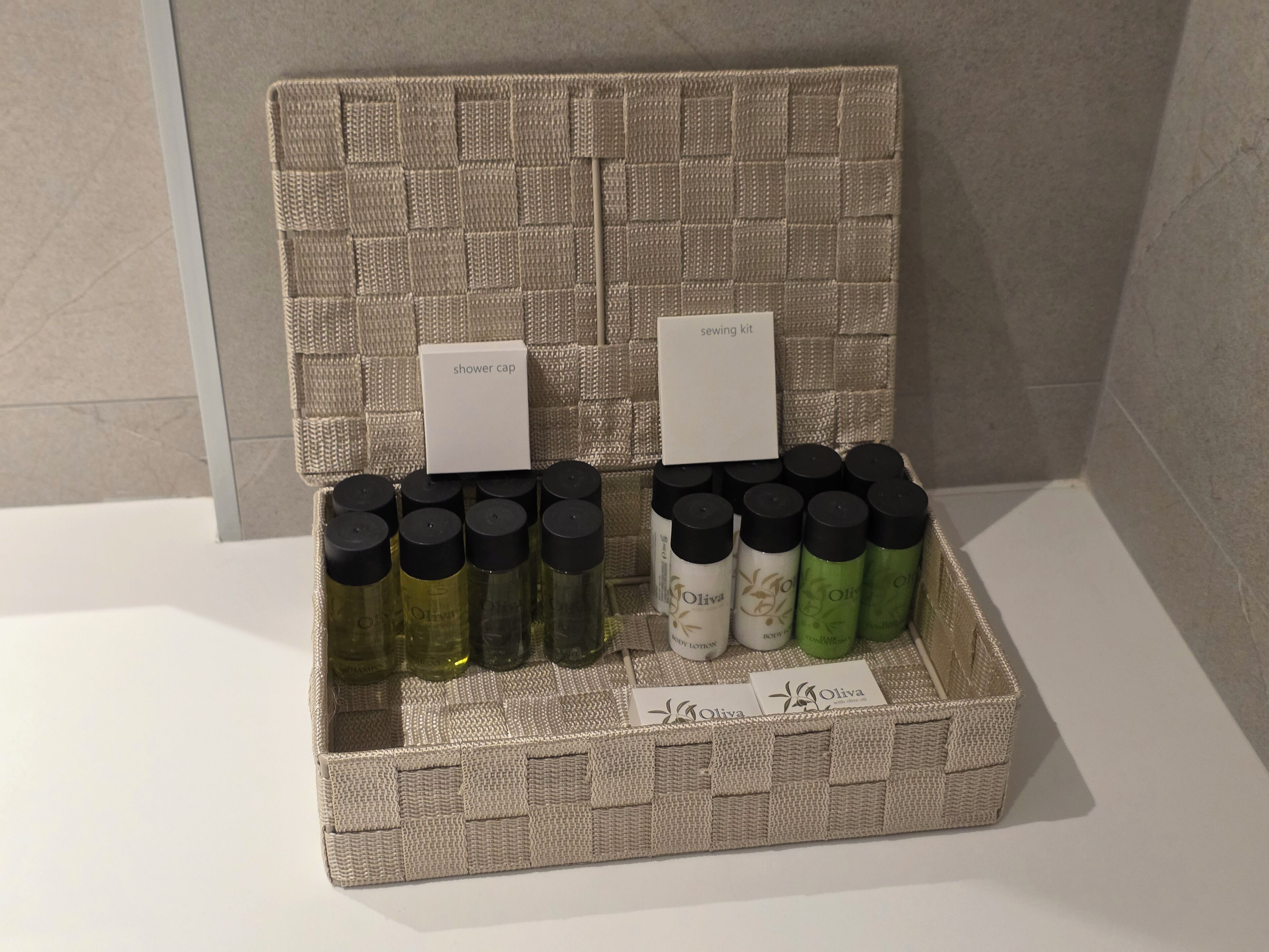A wicker basket containing various bottles of olive oil and a sewing kit.