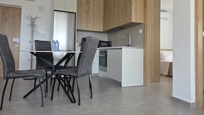 Una cocina moderna con armarios blancos, una isla central y una zona de comedor con sillas grises.