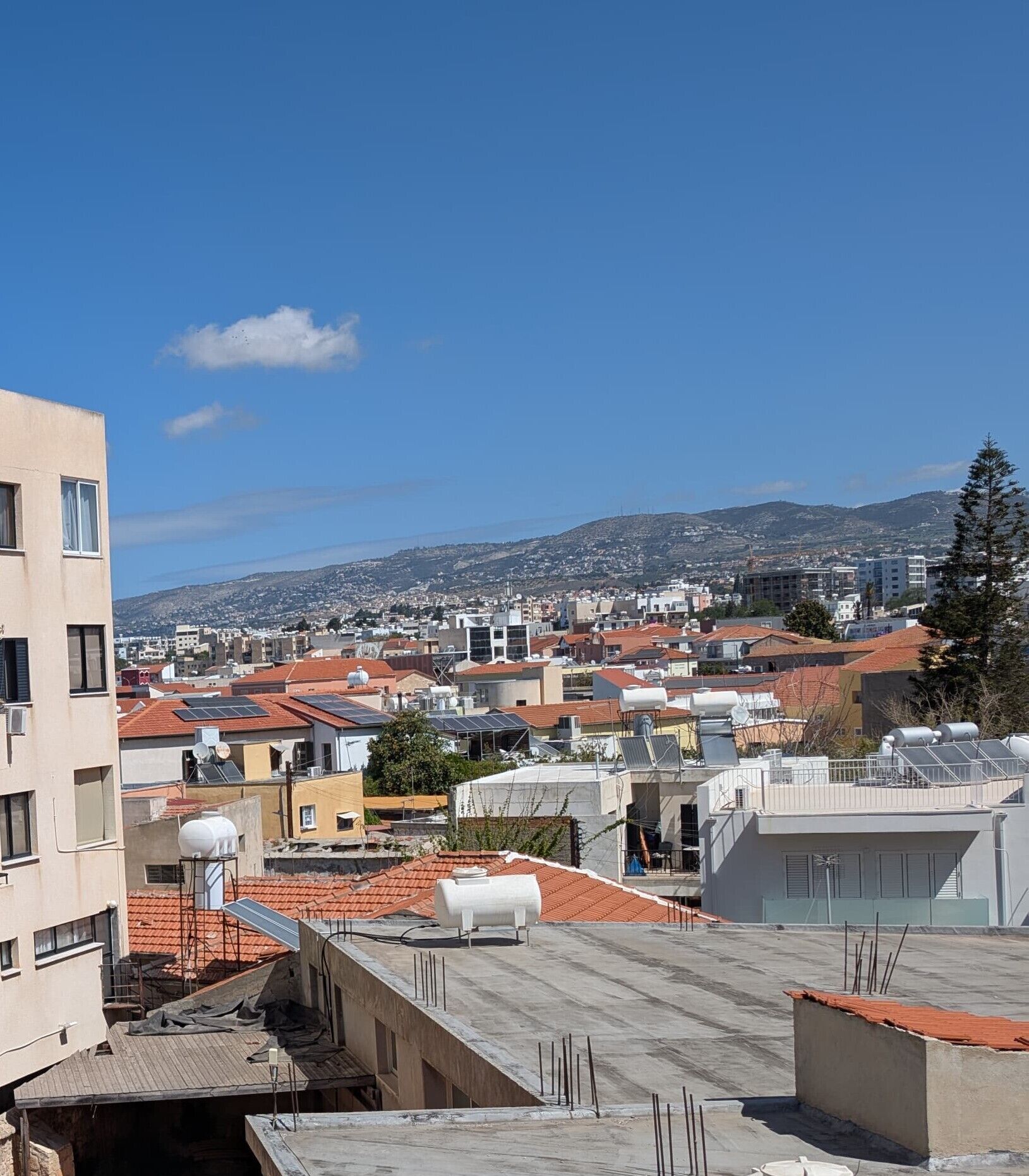 Un paisaje urbano con edificios residenciales y una colina destacada al fondo.